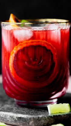 a close up of a drink in a glass on a table with limes around it