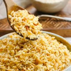 a wooden spoon full of rice in a bowl