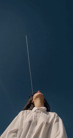 a woman is looking up at the sky with a kite in her hand as she flies through the air