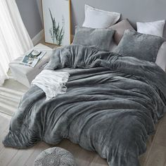 a bed with grey comforter and pillows in a bedroom