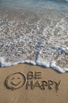 the word be happy written in the sand at the beach