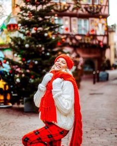 a woman is standing in front of a christmas tree