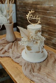 a white wedding cake sitting on top of a wooden table