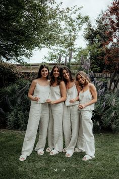 the bridesmaids are posing for a photo in their white jumpsuits