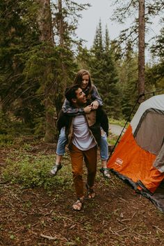 a man carrying a woman near a tent in the woods