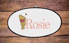 a cross stitch winnie the pooh sign hanging on a wooden wall with wood planks