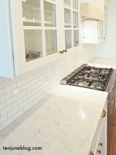 a kitchen with white cabinets and marble counter tops, along with a stove top oven