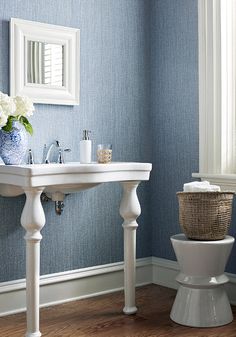 a white toilet sitting next to a sink in a bathroom under a window with blue walls