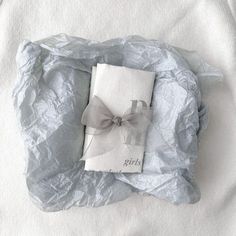 a book with a bow on it laying on a bed covered in crumpled paper next to a pillow