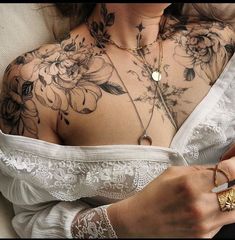 a woman with tattoos on her chest holding a cell phone