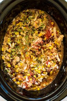 a crock pot filled with chicken, beans and corn