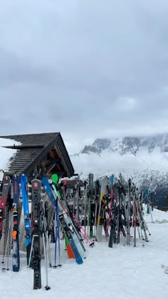 many skis are lined up in front of a small cabin on a snowy mountain