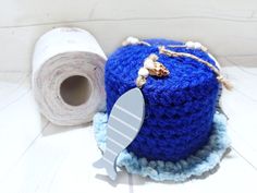 a blue crocheted pot holder next to a roll of toilet paper