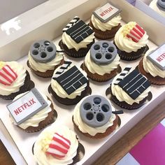 cupcakes decorated with movie related items are displayed in a box on a table