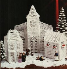 a crocheted christmas scene with people and snowmen in front of a church