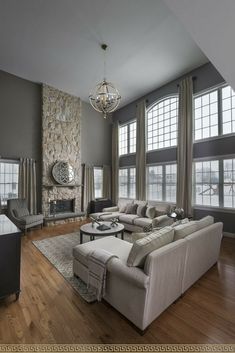 a living room filled with lots of furniture next to large windows and a stone fireplace