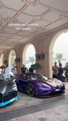 some very nice looking cars in a big room with people standing around them and talking to each other