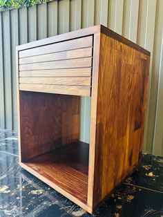 a wooden shelf sitting on top of a black marble floor next to a metal wall