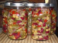 two jars filled with pickled vegetables sitting on top of a table