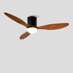 a black ceiling fan with wooden blades and two white balls on the blade, against a gray background