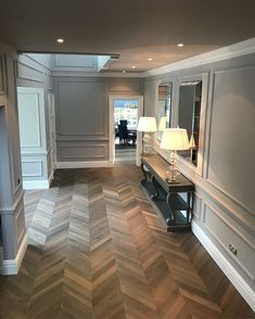 an instagram photo of a living room with herringbone wood flooring and gray walls