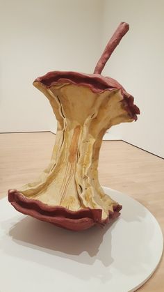 an apple sculpture sitting on top of a white plate next to a wooden flooring