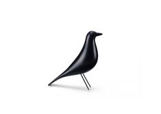 a black bird sitting on top of a metal stand in front of a white background