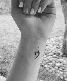 a woman's arm with a small heart tattoo on her left wrist and the word love