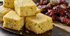 several pieces of cornbread on a plate next to dried cherries and cranberry sauce