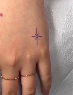 a woman's hand with a small star tattoo on it