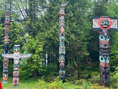 three totems in the woods with trees behind them