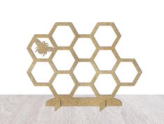 a gold hexagonal sculpture with a bee on it's back and two bees in the middle