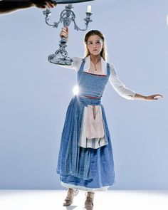 a woman dressed in blue is holding a chandelier