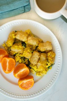 a plate with oranges and some food on it next to a cup of coffee