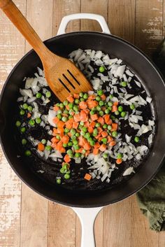 a skillet filled with rice, peas and carrots