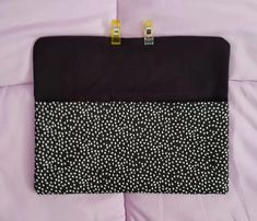 a black and white polka dot purse laying on a pink bed sheet with gold hardware