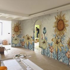 a man is painting a wall with sunflowers on it in an empty room