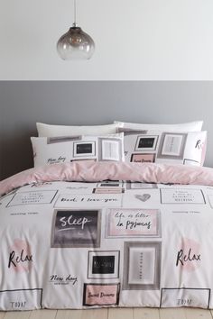 a bed with pink sheets and pillows on top of it next to a light fixture