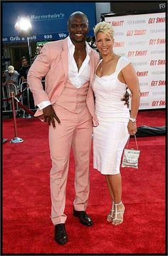 a man in a pink suit and woman in a white dress posing on the red carpet