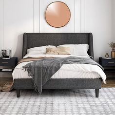 a bedroom with a bed, nightstands and a round mirror on the wall