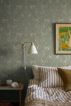 a bedroom with green wallpaper and striped bedding, two lamps on either side of the bed