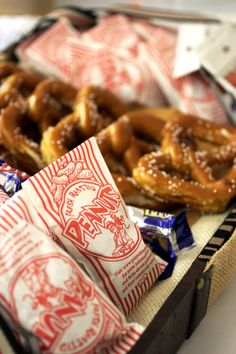 some pretzels are sitting in a box with candy bars on the table next to them