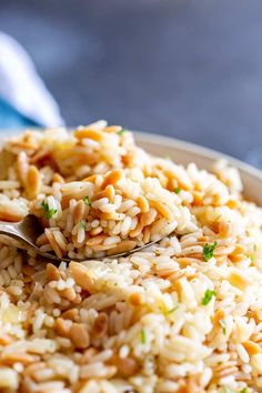 a bowl filled with rice and nuts on top of a blue table cloth next to a spoon