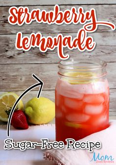 a mason jar filled with strawberry lemonade next to two lemons