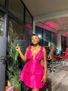 a woman in a pink dress standing next to a plant