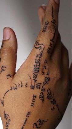 a person's hand with tattoos on it and writing all over the palm area