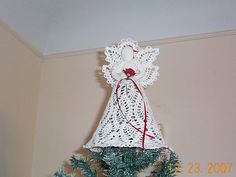 a crocheted angel on top of a christmas tree