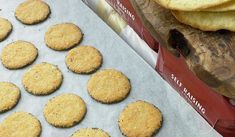 some cookies are sitting on a baking sheet next to an open box of crackers