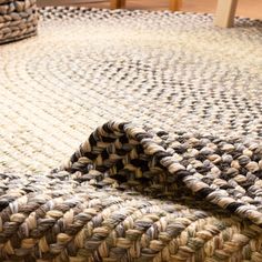 a close up of a rug on the floor with a chair in the back ground