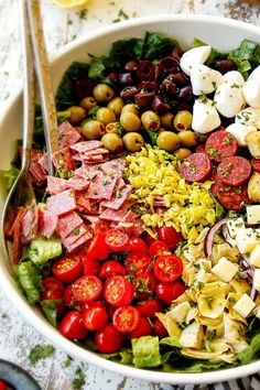 a large salad with olives, tomatoes, ham, cheese and other toppings